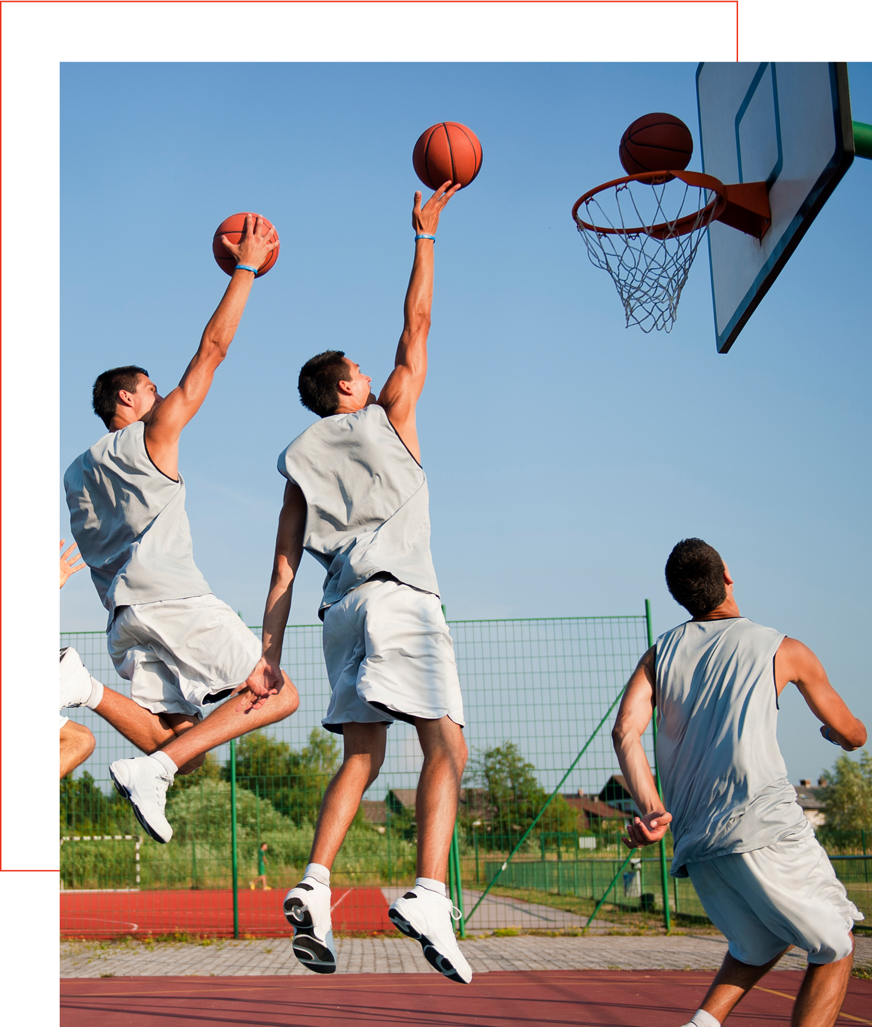 Three basketball players jumping towards hoop.