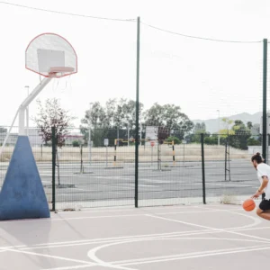 Person preparing to shoot basketball on outdoor court.