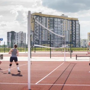 People playing volleyball on an outdoor court in an urban area.