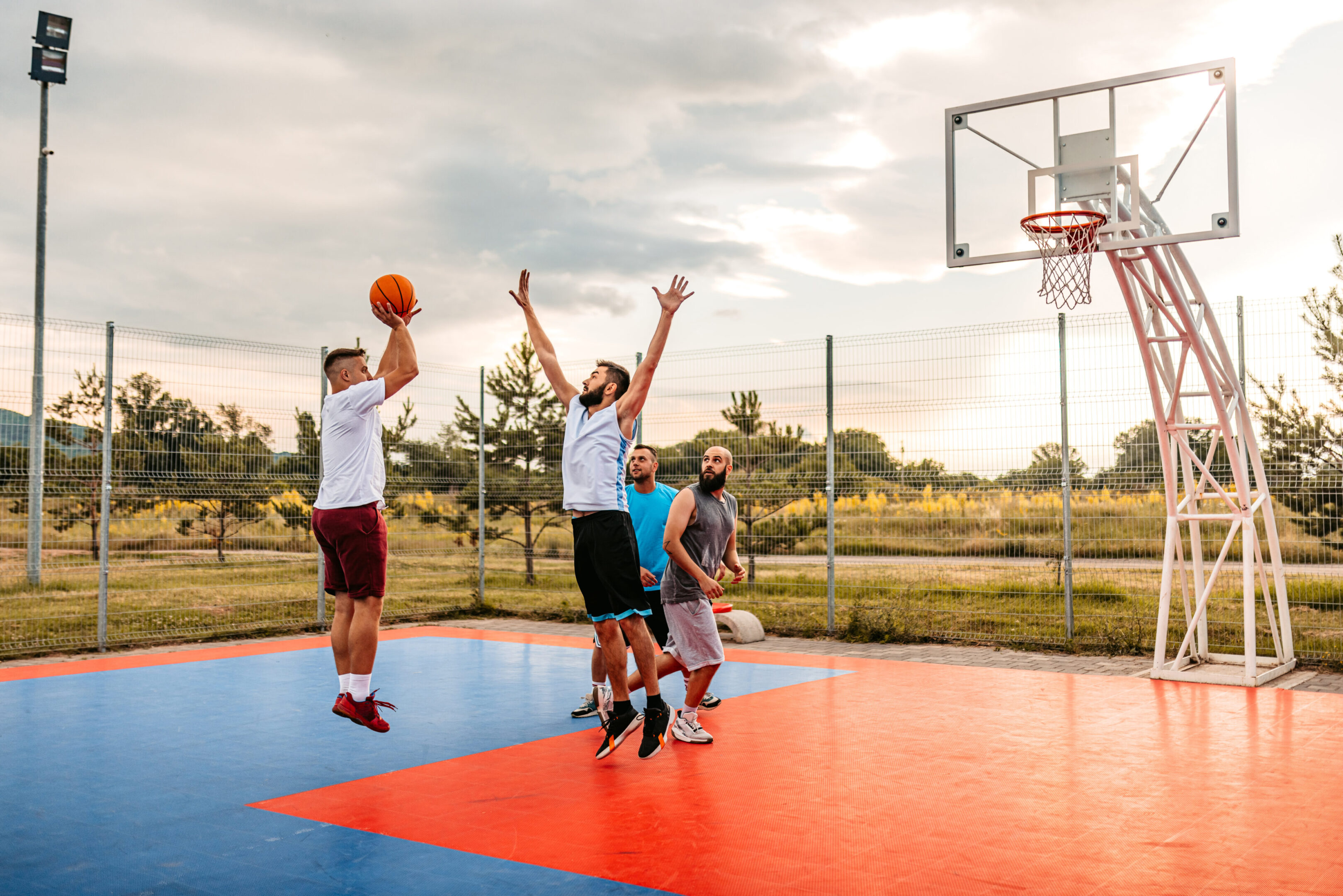 Men playing basketball on outdoor court.