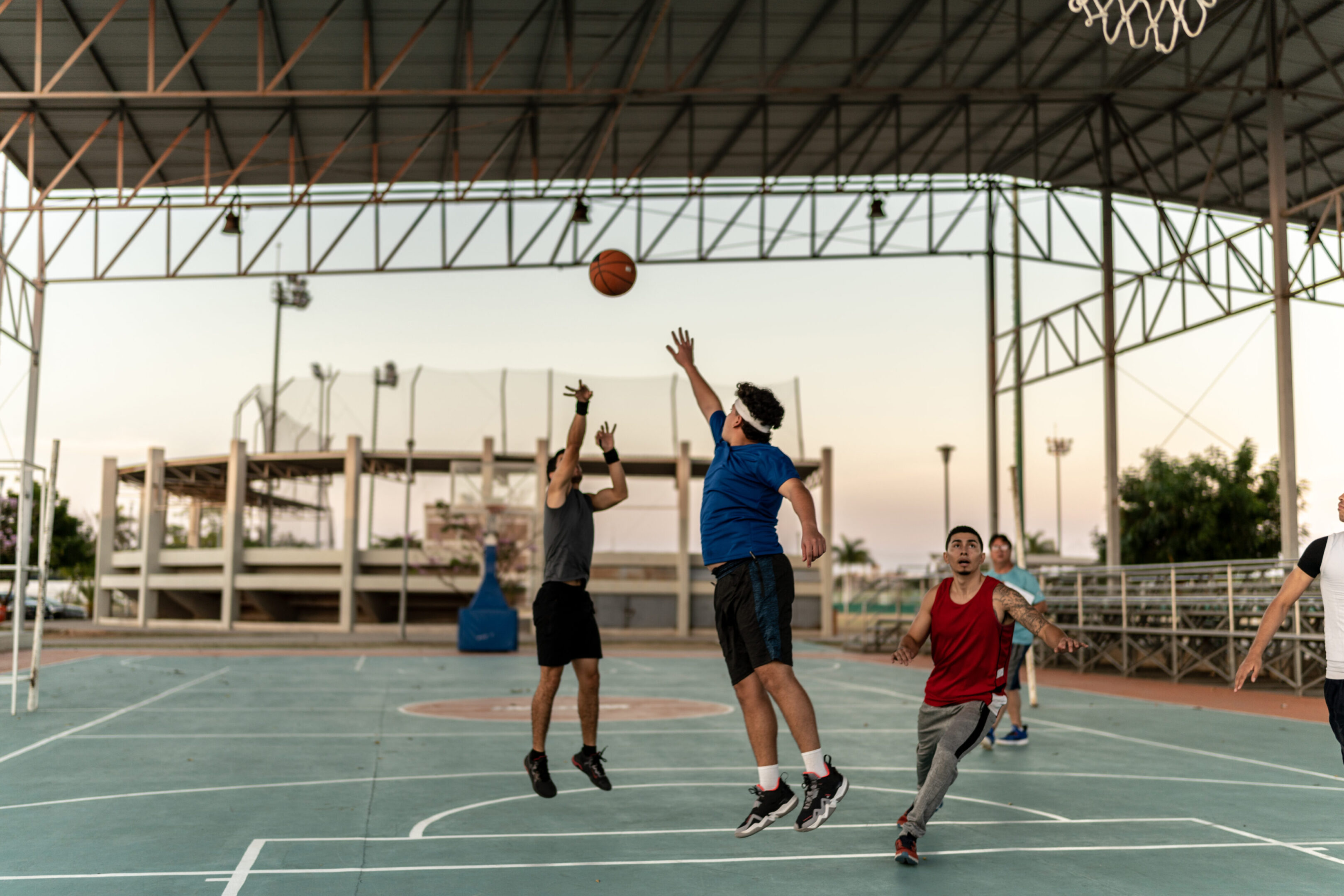 Outdoor basketball game under covered court.