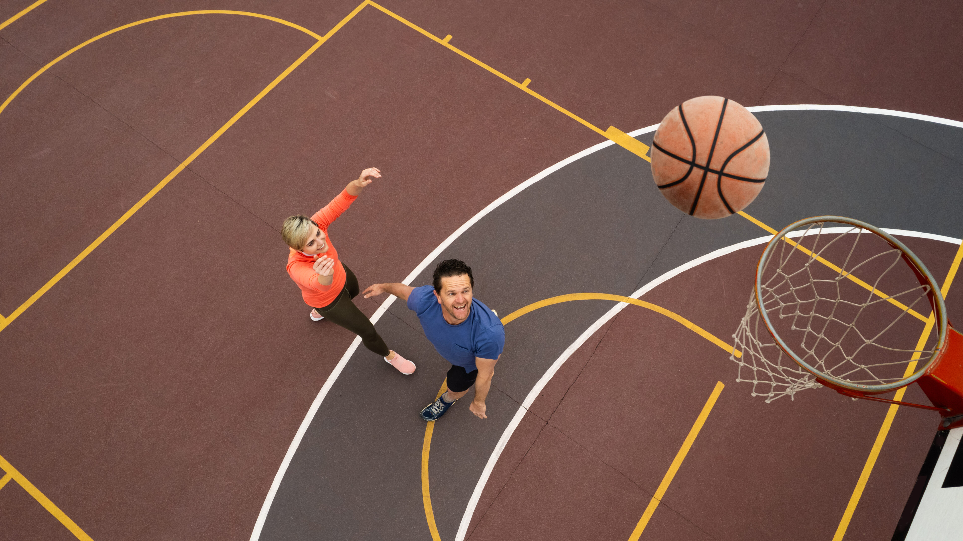Two people playing basketball on outdoor court.