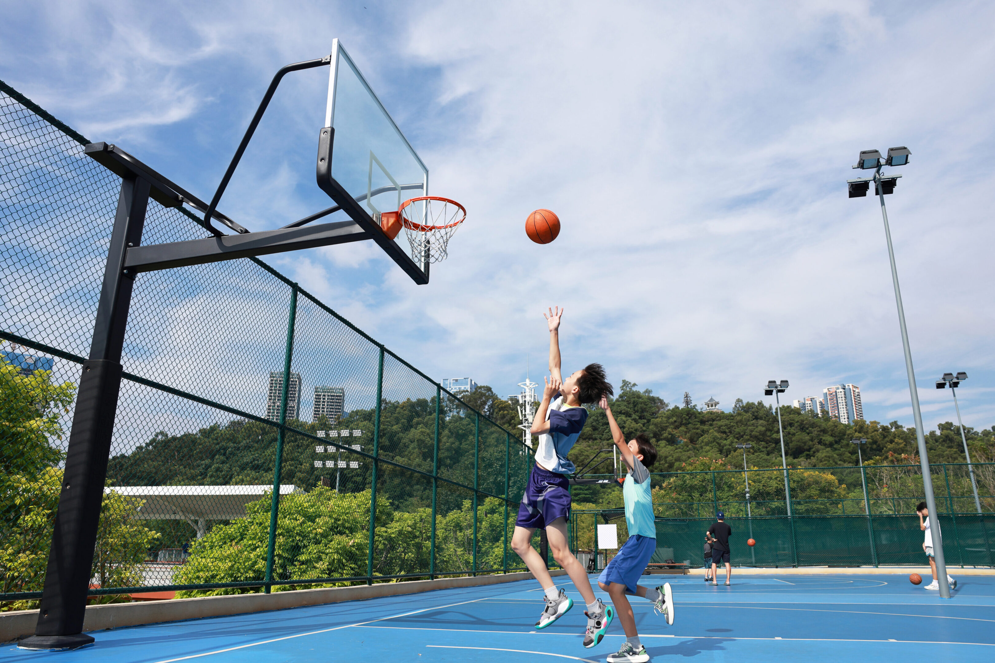 Players jumping for basketball shot outdoors.